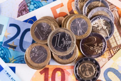Coins in denominations of 1 and 2 euros against the background of euro banknotes of various denominations