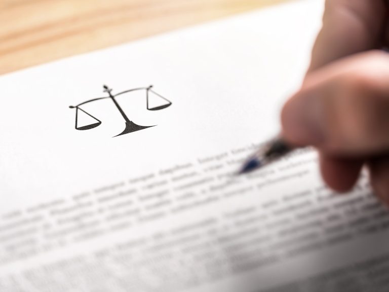 Attorney, lawyer, solicitor or jurist working on a business brief in law firm. Legal contract, clause or article paper. Man writing document with scale icon and sign with pen. Judge making decision.